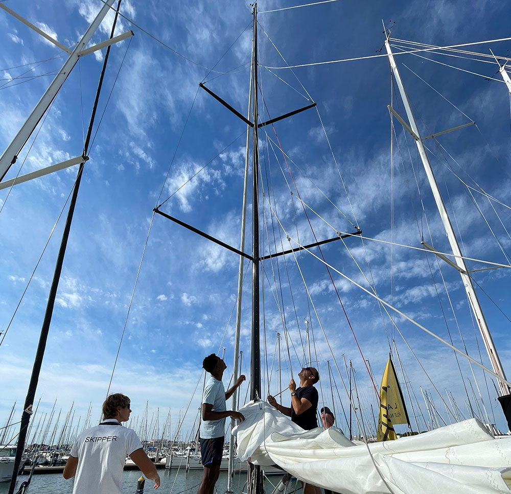 Personnes hissant la grande voile sur un voilier