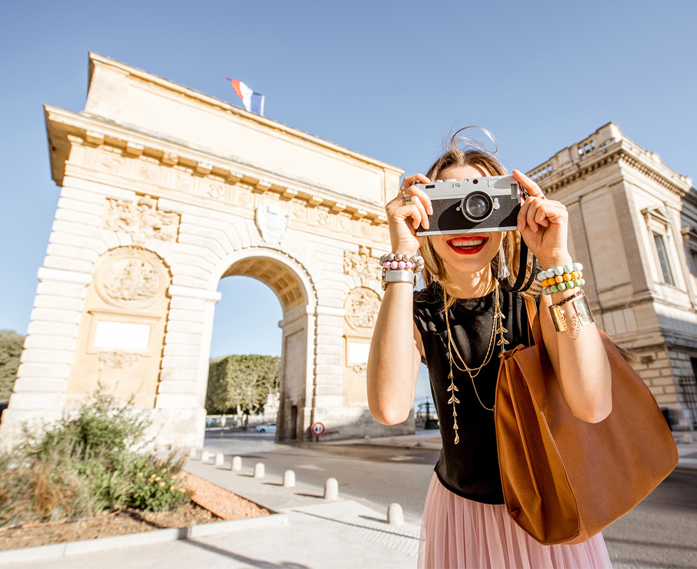 Femme avec un appareil photo devant l'arc de Triomphe de Montpellier
